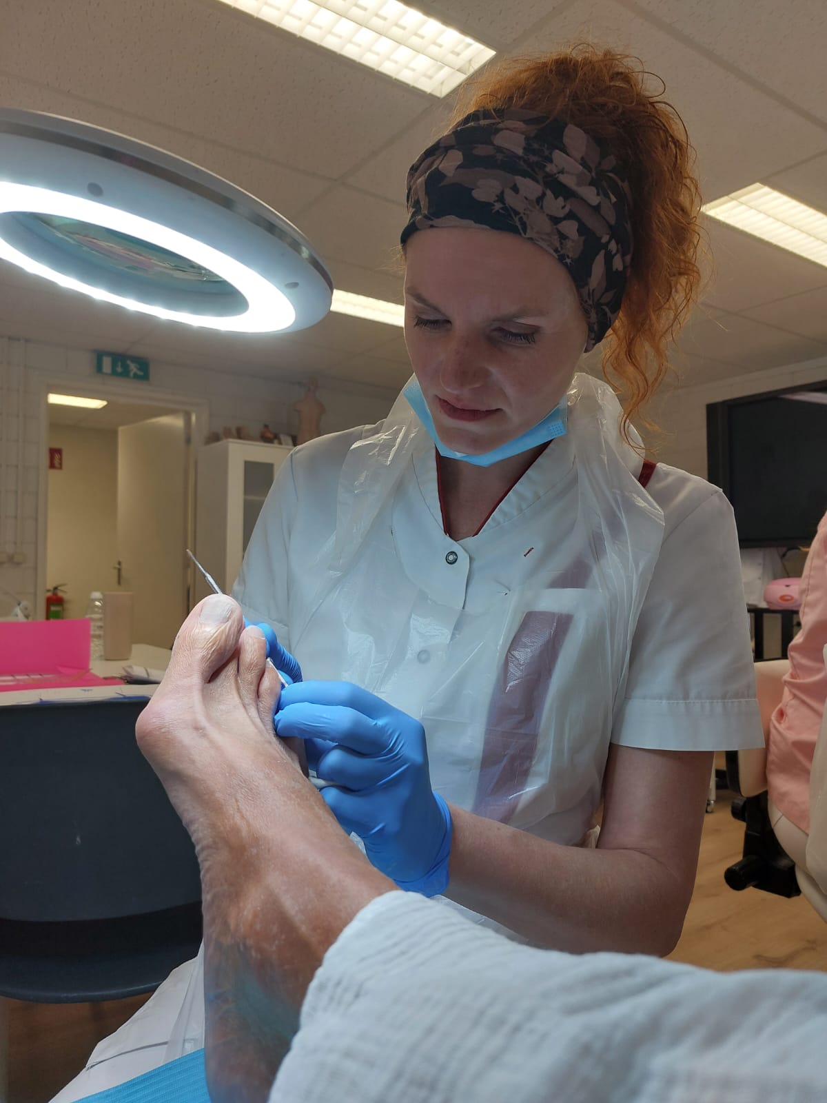 Lisetthe in witte werkjas behandelt de voet van een klant